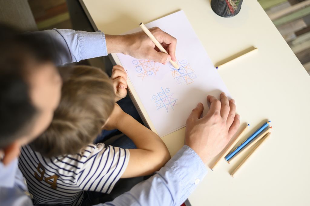 Brincadeira de antigamente: Pai segurando filho no colo e brincando de jogo da velha com ele