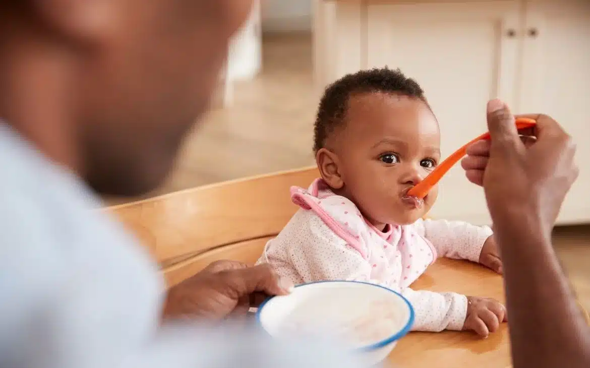 Pai dando papinha para bebê durante a introdução alimentar