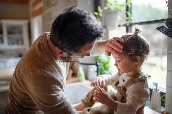 Pai medindo a febre de uma criança, prestando atenção aos sintomas de câncer infantil