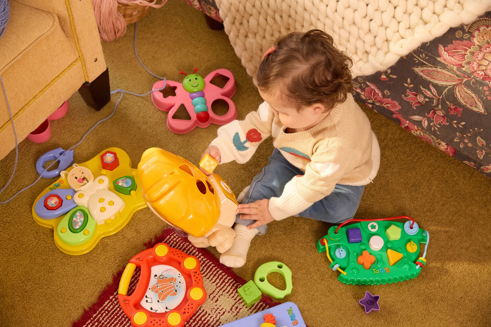 Bebê cercado por brinquedos educativos.